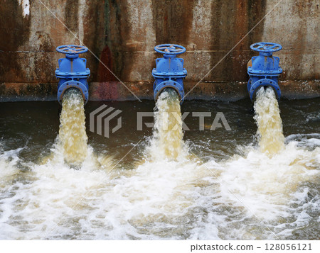 Industrial drainage system with five blue pipes discharging water into a reservoir. Concept of water management, wastewater treatment, and environmental engineering, spillway Industrial drainage system with five blue pipes discharging water into a reservoir. Concept of water management, wastewater treatment, and environmental engineering, spillway 128056121