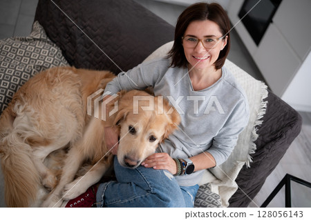 Happy Woman Hugging An Adorable Dog Relaxes On The Sofa At Home 128056143