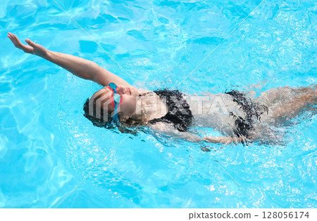 Young Girl Swims Backstroke In Outdoor Pool Young Girl Swims Backstroke In Outdoor Pool 128056174