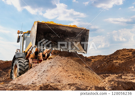 Bulldozer moving earth at a construction site during daylight hours Bulldozer moving earth at a construction site during daylight hours 128056236