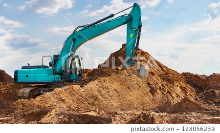 Excavator digging on a construction site under a clear blue sky during daylight hours Excavator digging on a construction site under a clear blue sky during daylight hours 128056239