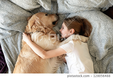 Happy Little Girl Lying In Embrace With Dog In Bed 128056488