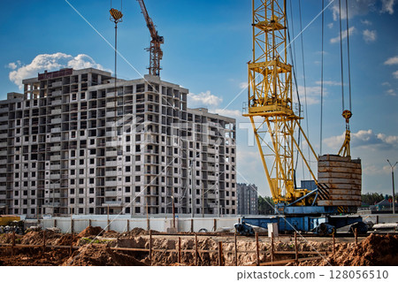 Construction site showing a tower crane lifting materials for a new building in a city neighborhood Construction site showing a tower crane lifting materials for a new building in a city neighborhood 128056510