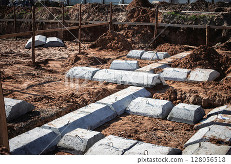 Concrete foundations being laid for a new building in an urban construction site during daylight Concrete foundations being laid for a new building in an urban construction site during daylight 128056518