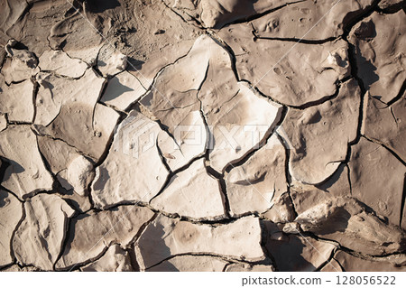 Dry cracked earth reveals unique textures in an arid landscape during daylight hours 128056522