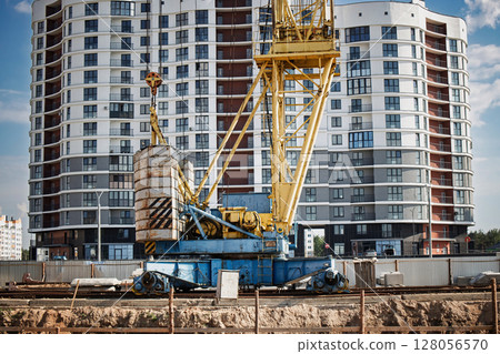 Heavy construction crane stands tall against modern apartment buildings during vibrant daylight hours 128056570
