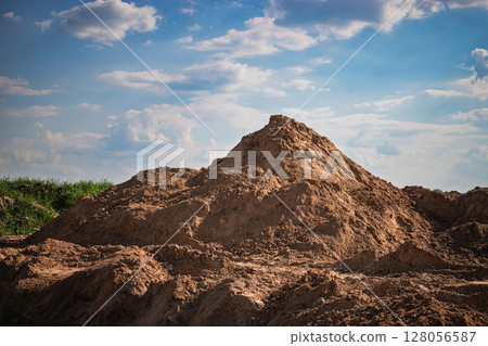 Construction site featuring a large mound of dirt under a blue sky with fluffy clouds in the afternoon Construction site featuring a large mound of dirt under a blue sky with fluffy clouds in the afternoon 128056587
