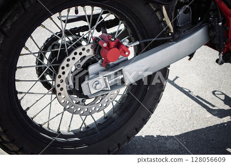 Close-up view of a motorcycle rear wheel and braking system on a sunny day outdoors Close-up view of a motorcycle rear wheel and braking system on a sunny day outdoors 128056609