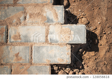 Brick pathway under construction in sunny environment with scattered dirt and gravel nearby 128056618