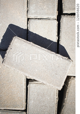 Gray concrete bricks arranged with one tilted on a sunny day in an outdoor construction area 128056620