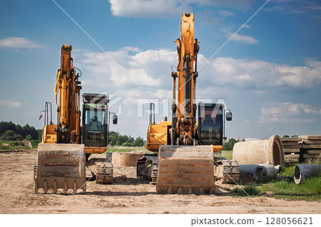 Excavators working on a construction site under a clear blue sky at mid-day Excavators working on a construction site under a clear blue sky at mid-day 128056621