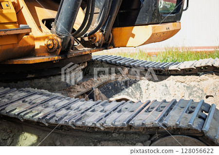 Excavator machinery with tracks and gears on construction site during daylight Excavator machinery with tracks and gears on construction site during daylight 128056622
