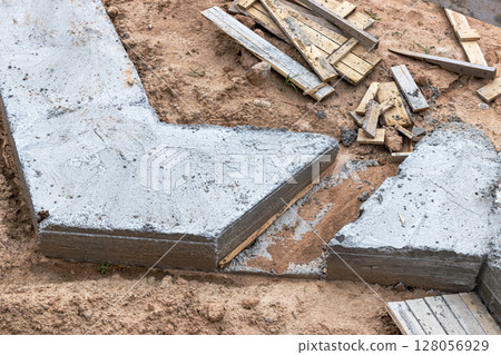 Reinforced concrete foundation of a modern monolithic residential building. Prepared formwork with reinforcing mesh for pouring concrete. Dirt and clay at the construction site. 128056929