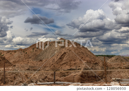Heap of earth sand and clay at the construction site against the sky. Earthworks at the construction site. 128056930