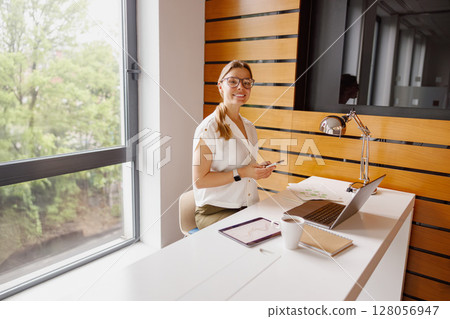 A Bright and Inviting Office Environment Featuring a Professional Woman Engaged in Her Work A Bright and Inviting Office Environment Featuring a Professional Woman Engaged in Her Work 128056947