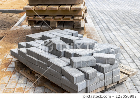 Storage of paving slabs on pallets at the construction site. Ready-to-install concrete paving slabs. Finished products warehouse. Storage of paving slabs on pallets at the construction site. Ready-to-install concrete paving slabs. Finished products warehouse. 128056992