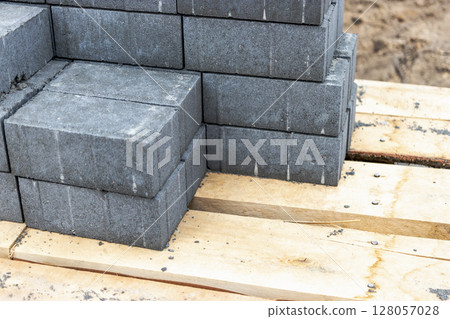 Storage of paving slabs on pallets at the construction site. Ready-to-install concrete paving slabs. Finished products warehouse. 128057028