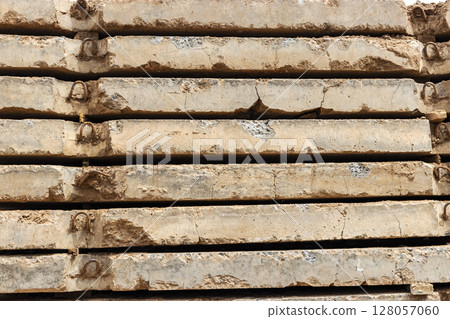 Old reinforced concrete road slabs stacked on a construction site for later use. Temporary road surface. Old reinforced concrete road slabs stacked on a construction site for later use. Temporary road surface. 128057060