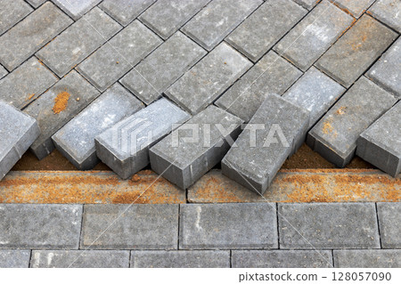 Pavement repairs and paving slabs laying on the prepared surface, with tile cubes in the background. Laying paving slabs in the pedestrian zone of the city. Paving slabs and curbs. 128057090