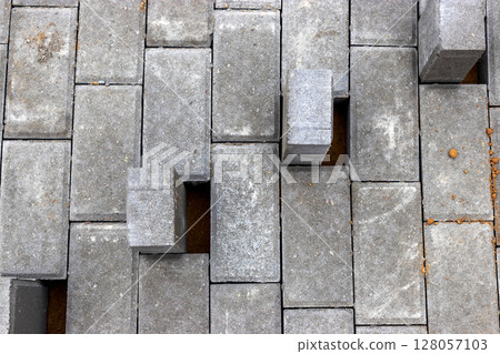 Pavement repairs and paving slabs laying on the prepared surface, with tile cubes in the background. Laying paving slabs in the pedestrian zone of the city. Paving slabs and curbs. Pavement repairs and paving slabs laying on the prepared surface, with tile cubes in the background. Laying paving slabs in the pedestrian zone of the city. Paving slabs and curbs. 128057103