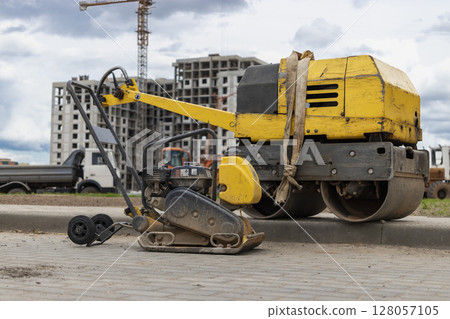 Vibratory rammer with vibrating plate on a construction site. Manual roller. Compaction of the soil before laying paving slabs. close-up. 128057105