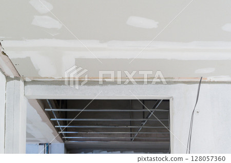 Gypsum board ceiling edges with smooth plastering reveal ongoing interior renovation electrical wire work highlights future building ceilings scene of construction progress 128057360