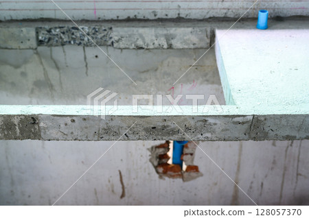 Detail of concrete foundation during house renovation. construction site shows plumbing pipe installation and repair work on floor structure for home improvement 128057370