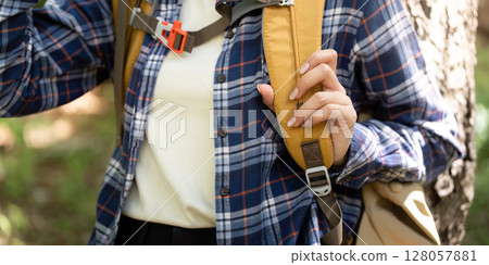 Outdoor Adventure. Young woman adjusting backpack straps in nature. 128057881