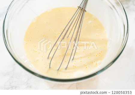 With a hand whisk, the measured ingredients come together - expertly mixed to prepare the cake batter for this delightful bundt cake. With a hand whisk, the measured ingredients come together - expertly mixed to prepare the cake batter for this delightful bundt cake. 128058353