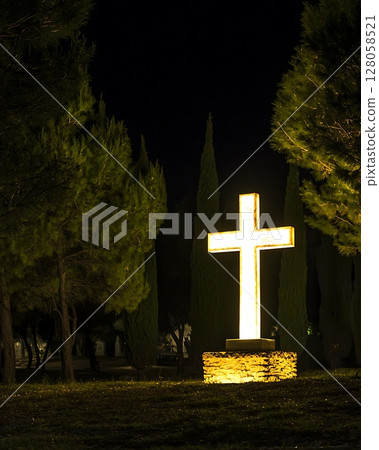 A large white cross is lit up in the dark 128058521