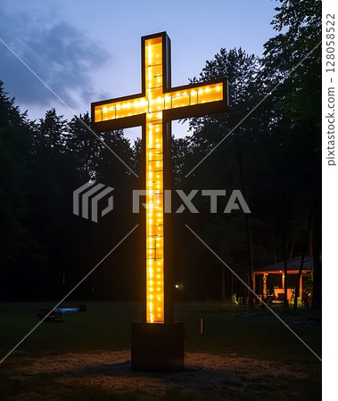 A large illuminated cross is lit up in the woods at night 128058522