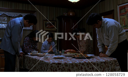 A family of five is gathered around a table with a turkey on it 128058729
