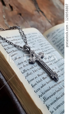 A silver cross necklace is on top of a book A silver cross necklace is on top of a book 128058807