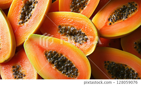 Fresh ripe papaya halves with vibrant orange flesh and black seeds arranged closely. Juicy tropical fruit showcasing natural texture. 128059076