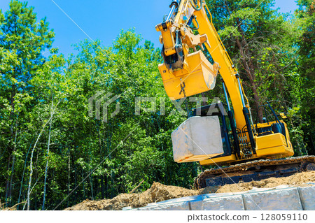 Heavy machinery is actively lifting concrete block at construction site on build retaining walls Heavy machinery is actively lifting concrete block at construction site on build retaining walls 128059110