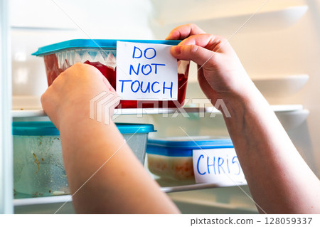 Office fridge with angry Do Not Touch My Food stickers on meal containers. Workplace humor, coworking content. Office fridge with angry Do Not Touch My Food stickers on meal containers. Workplace humor, coworking content. 128059337