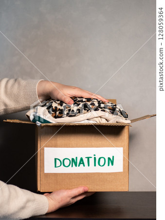 Woman gives her old clothes to charity, helping people in need who are caught up in military action. Woman gives her old clothes to charity, helping people in need who are caught up in military action. 128059364