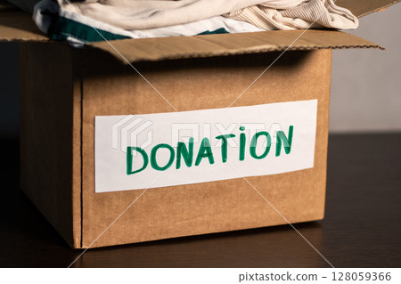 Cardboard box full of clothing ready for donation. Modern eco friendly habits and conscious consumption. Zero waste. Cardboard box full of clothing ready for donation. Modern eco friendly habits and conscious consumption. Zero waste. 128059366