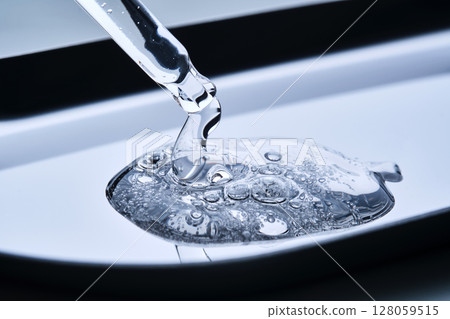 A pipette with hyaluronic serum on a blue background. 128059515