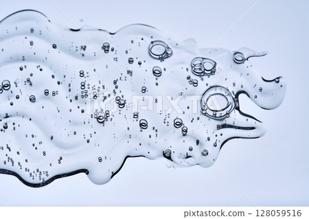 A beautiful drop of cosmetic product with bubbles on a blue background. 128059516