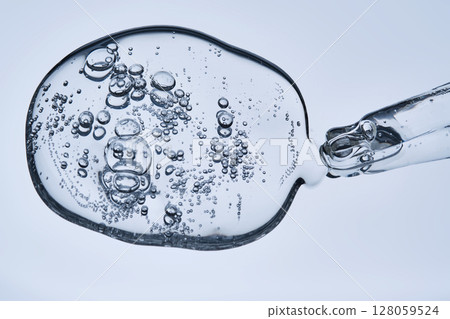 A pipette with hyaluronic serum on a blue background. A pipette with hyaluronic serum on a blue background. 128059524