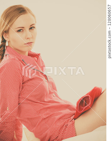 Woman feeling stomach cramps lying on bed 128060657