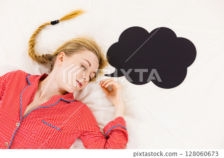 Young woman lying on bed wearing pajamas 128060673