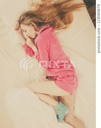 Young woman lying on bed wearing pajamas 128060679