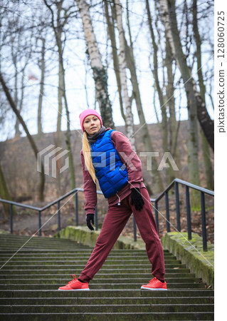 Woman wearing sportswear exercising outside during autumn 128060725