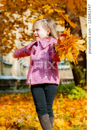 Little girl holding yellow autumn leaves, smiling outdoor park. Seasonal joy child happiness concept Little girl holding yellow autumn leaves, smiling outdoor park. Seasonal joy child happiness concept 128061347