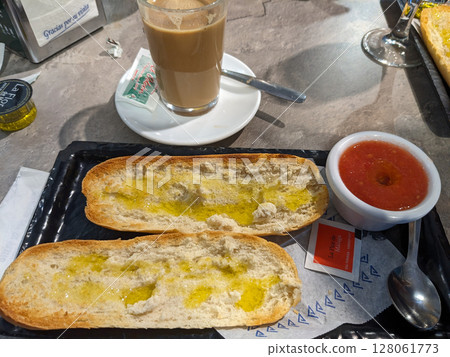 A delicious breakfast spread featuring toasted bread with olive oil, tomato, and a cafe con leche. Perfect start. A delicious breakfast spread featuring toasted bread with olive oil, tomato, and a cafe con leche. Perfect start. 128061773