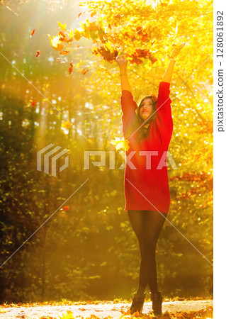 woman relaxing in autumn park throwing leaves up in the air 128061892