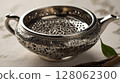 Antique silver handcrafted bowl with floral decoration and spices on light tablecloth 128062300
