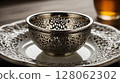 Empty etched metal teacup sitting on matching saucer, enjoying afternoon tea 128062302